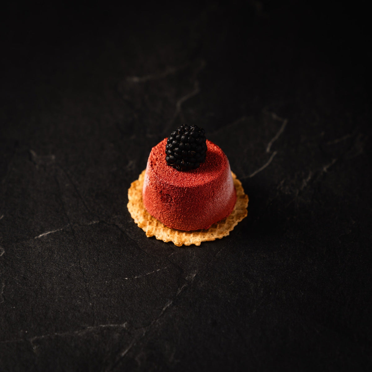 rotes Mousse-Törtchen mit Brombeere auf Waffelboden