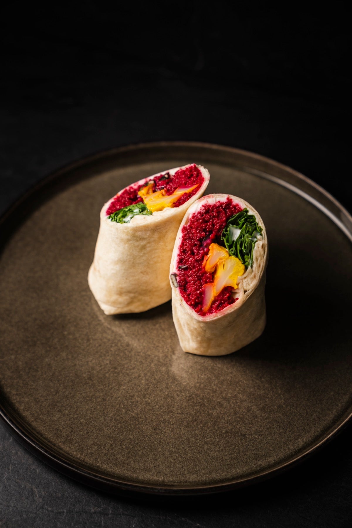 Mini Cous Cous Wraps mit rotem Couscous und Spinat auf einem Teller