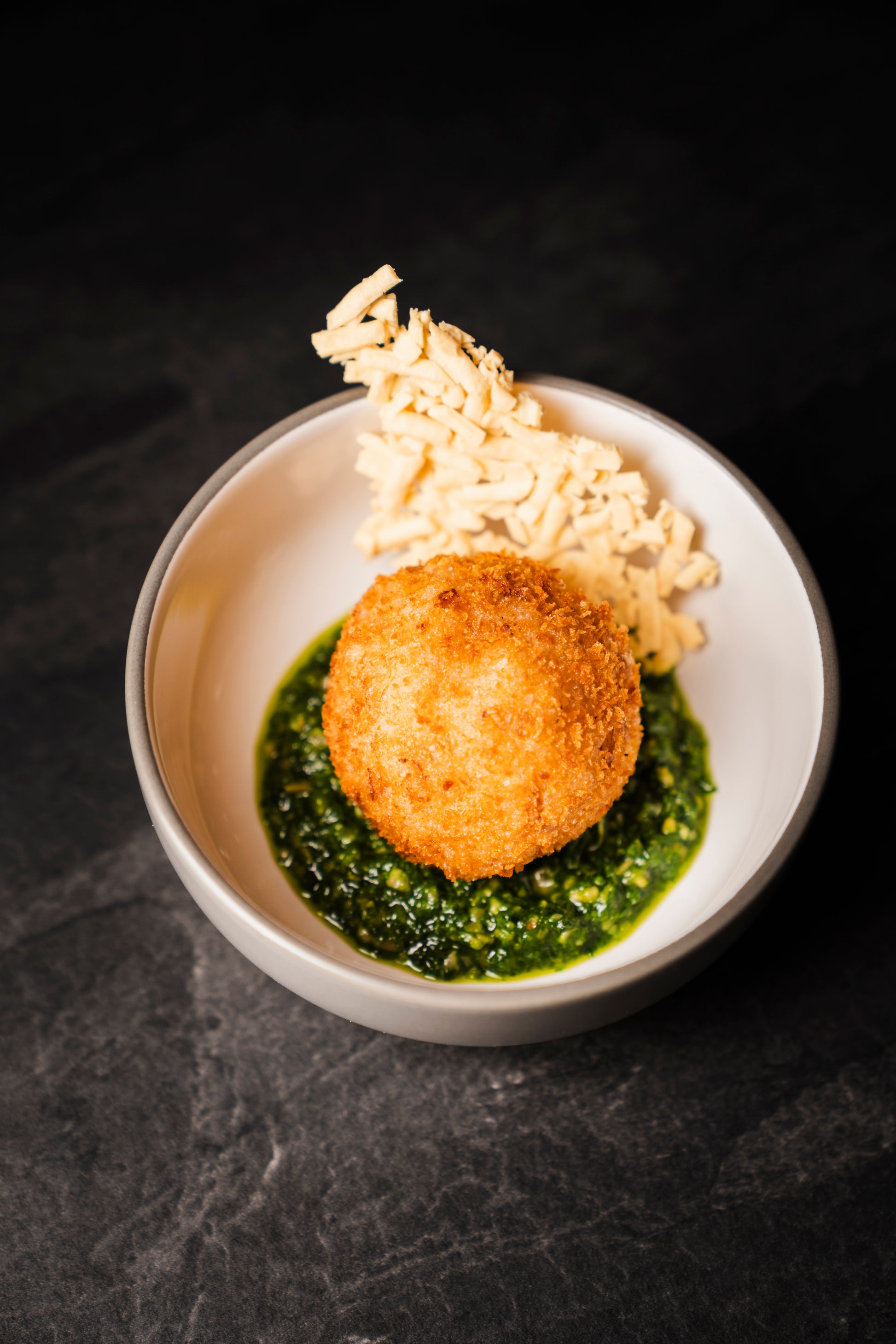 Trüffel-Arancini auf grünem Pesto in einer Schale