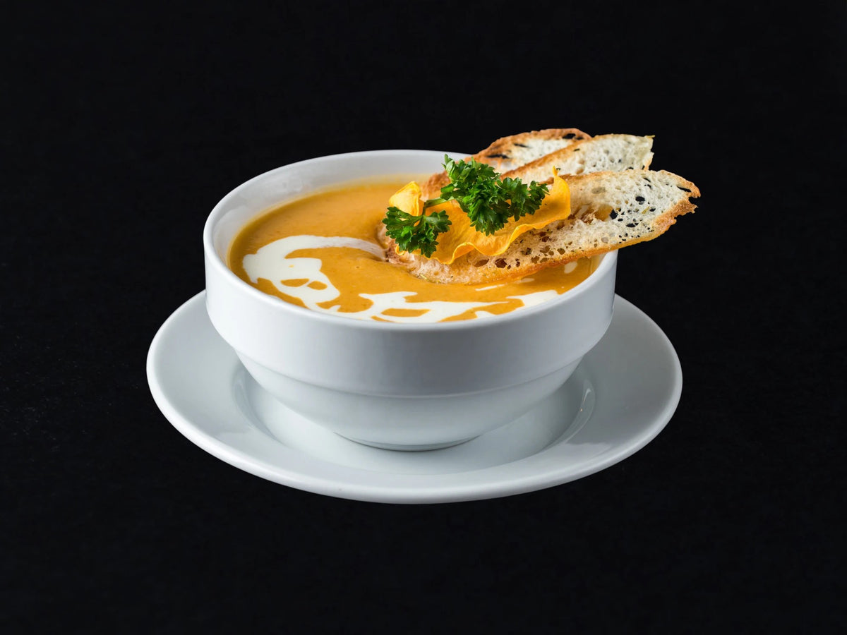Cremige Suppe in weißer Schale mit Brotchips (Serviervorschlag)